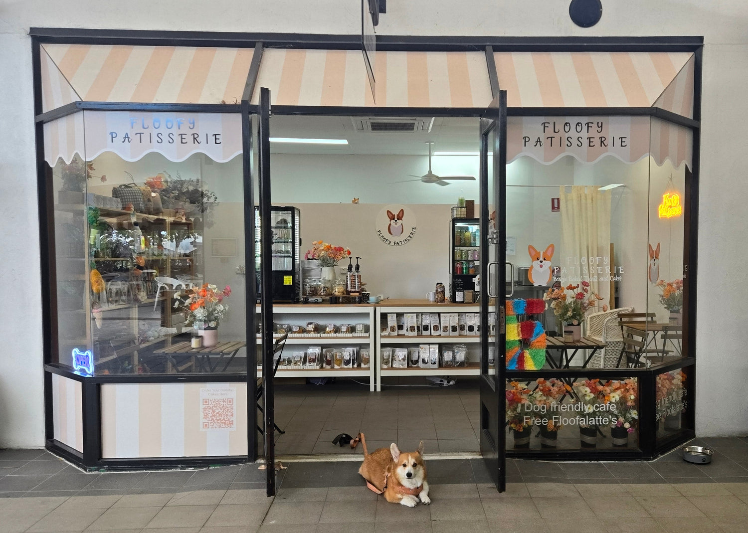 Front view of a patisserie with an open door, displaying various baked goods and decor.